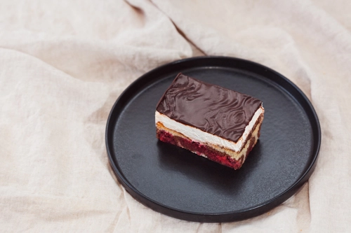 Stückchen Donauwelle mit einer Schicht aus dunkler Schokolade, süßer Sahne, zweifarbigem Marmoreuchenteig und saftigen Kirschen – ein zeitloser Kuchenklassiker der Bäckerei Müller