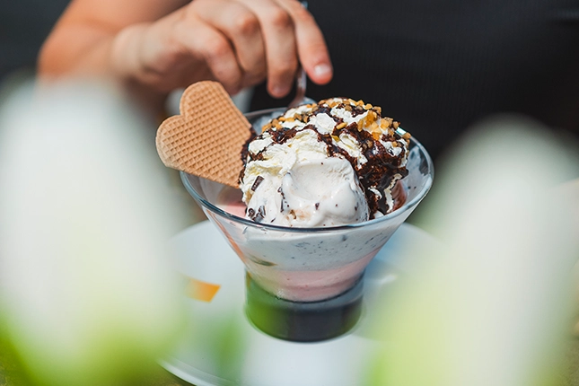 Gemischte Eisvariation aus Erdbeer- und Milcheis und Erdbeersauce, mit Krokantstreuseln und Waffel.