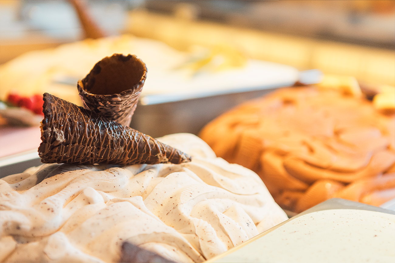 Nahaufnahme der Eisvariationen der Bäckerei Müller. Auf einer Sorte sind zwei dunkle, in Schokolade gehüllte Eishörnchen zu erkennen.