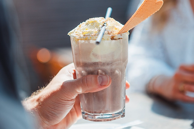 Eisschokolade auf Basis von kaltem Kakao mit Milch, Vanilleeis und Sahne. Serviert wird dieser mit Strohhalm und Waffel.