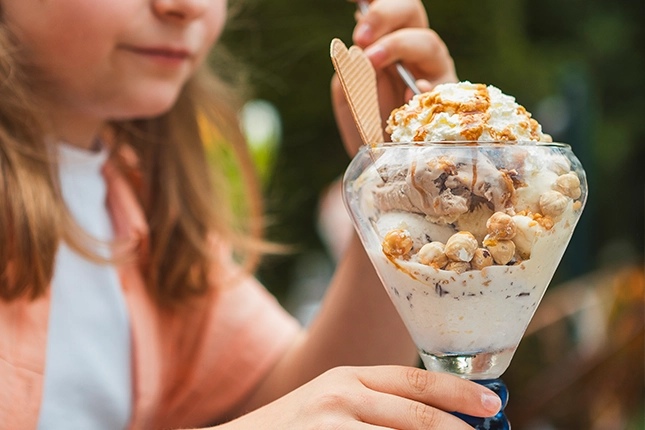 Nussbecher mit Waffeln, großer Sahnehaube, ganzen Haselnüssen und Karamellsauce verziert.