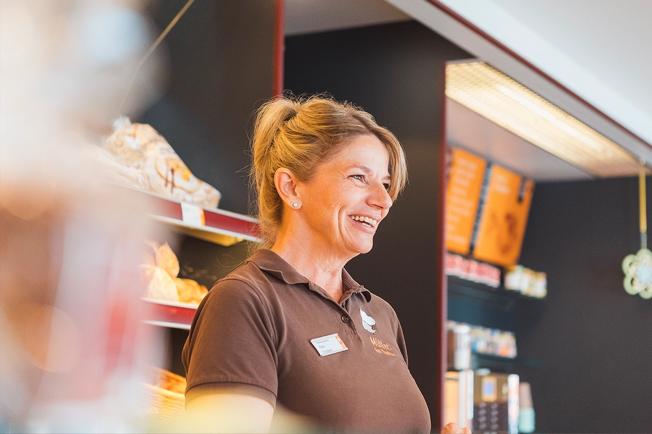 Portrait einer lächelnden Mitarbeiterin in der Schwabmünchner Fuggerstraße, die gerade einen Kunden bedient.