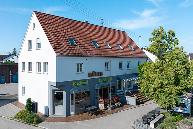 Außenaufnahme der Filiale und des Stehcafés in der Mindelheimer Straße in Schwabmünchen. Neben dem Eingang ist auch der kleine bestuhlte Außenbereich zu sehen.