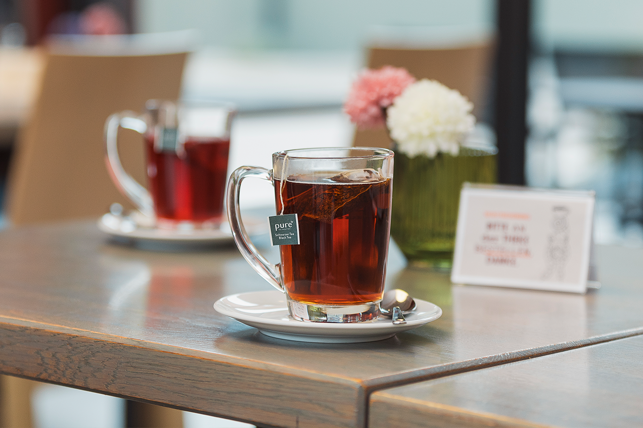 Teetasse mit heißem Tee, der in der Filiale in Langerringen serviert wurde. Im Hintergrund befindet sich eine weitere Teetasse. Ebenso zeichnen sich die liebevollen Details wie ein paar frische Blumen auf dem Tisch ab, die für das gemütliche Flair in der Filiale sorgen.