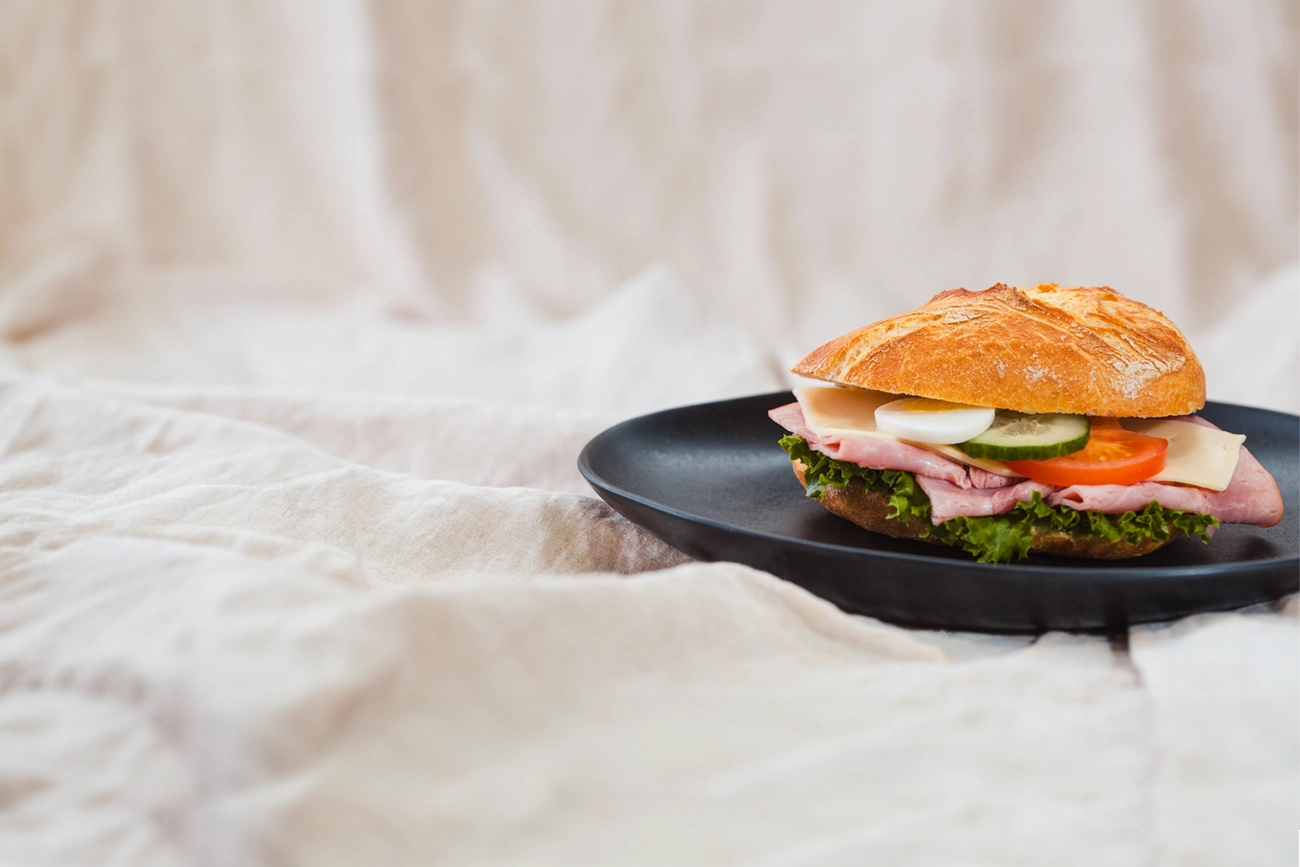 Das belegte Sandwich der Bäckerei Müller vereint knuspriges Brot mit herzhaftem Belag aus Schinken, Ei, Tomate, Gurke und Käse. Perfekt für einen Snack zwischendurch oder eine schnelle Mahlzeit.