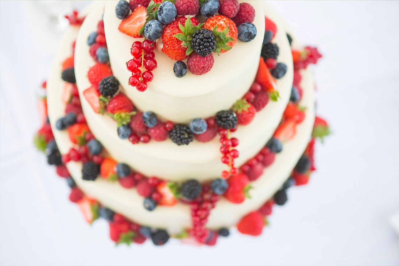 Detailaufnahme einer Beeren-Hochzeitstorte, die von Brombeeren, Blaubeeren, Johannisbeeren, Himbeeren und Erdbeeren verziert wurde.