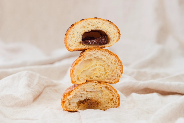 Turm aus drei unterschiedlichen Croissants, die in der Hälfte aufgeschnitten und auf einem Leinentuch drapiert wurden.