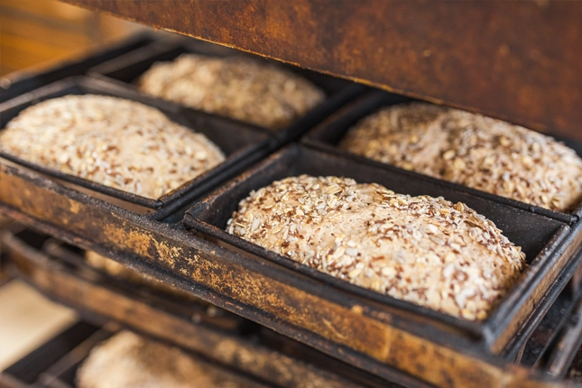 Brotkästen mit Brot und Gesäme im Ofen, das bereit sind gebacken zu werden.