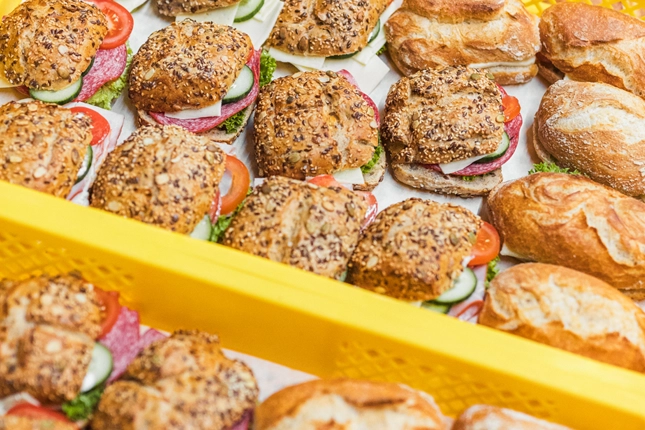 Nahaufnahme diverser Snacks, die gerade frisch belegt und für den Versand in die einzelnen Filialen vorbereitet wurden.