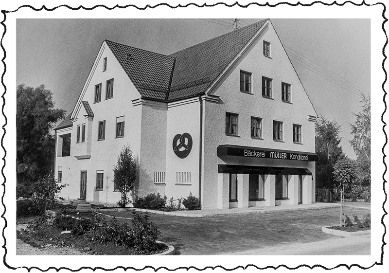 Altes Foto, das 1984 von dem Verkaufsstandort und der Backstube in Langerringen aufgenommen wurde. An der linken Seite ist eine Breze zu sehen, die bis heute noch an der Gebäudefassade angebracht ist.